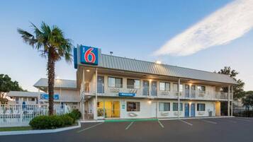 A motel with a '6' sign, a 'Welcome' sign, and a parking lot.