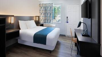 A hotel room with a bed, bedside tables, a desk, a chair, a TV, and a door.