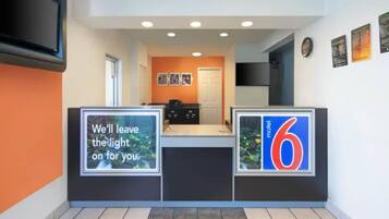 A hotel reception area with a counter, a door, and a wall with a number '6' sign.
