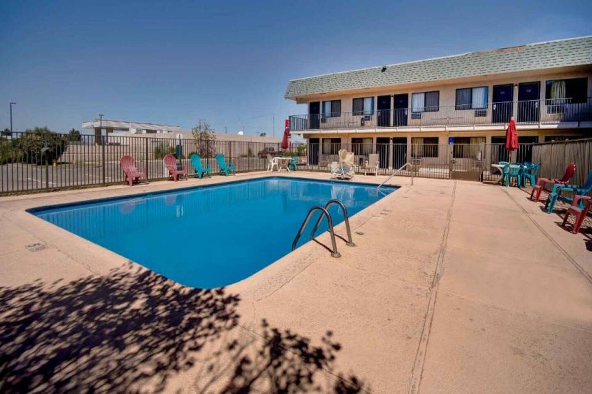 Una piscina con lettini e un edificio sullo sfondo.