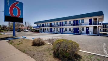 A motel with a large sign, multiple rooms, and a parking lot.