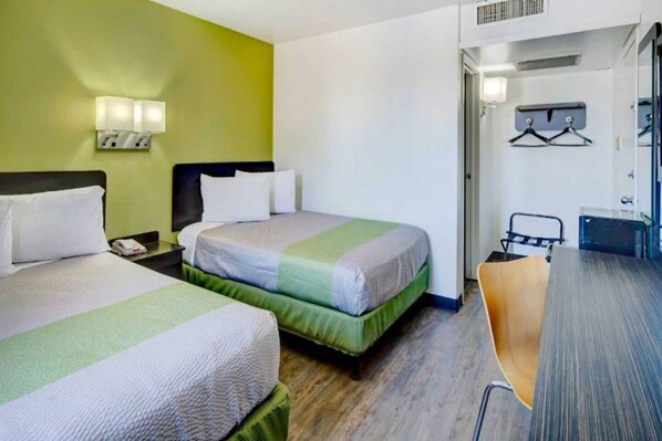 A hotel room with two beds, a desk, and a chair.