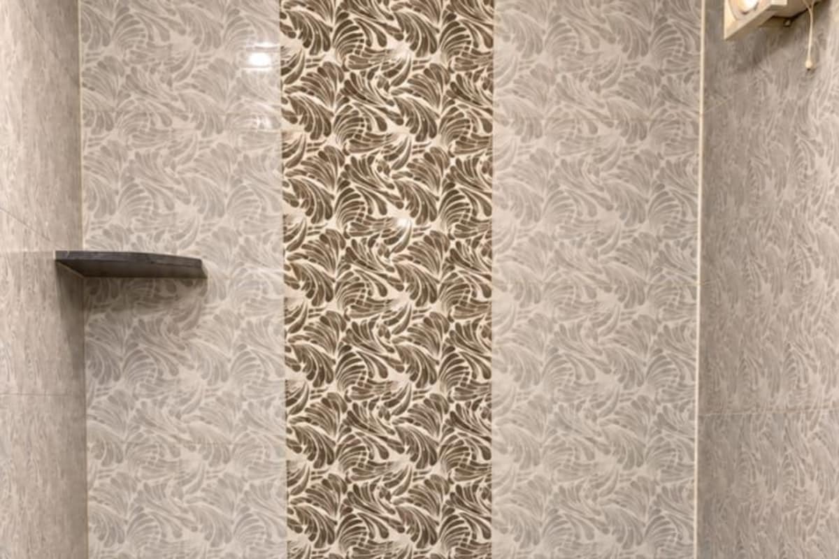Un baño con inodoro, ducha y una pared decorada con un diseño ornamental.