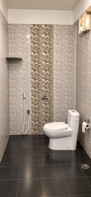 Un baño con inodoro, ducha y una pared decorada con un diseño ornamental.