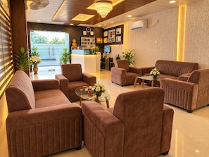 A hotel lobby with seating, a reception desk, and a view of the outdoors.