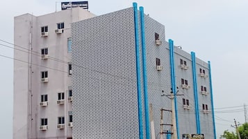 Ein mehrstöckiges Gebäude mit einer gemusterten Fassade, Klimaanlagen und einem Schild mit der Aufschrift 'Chocolat Inn Grand'.