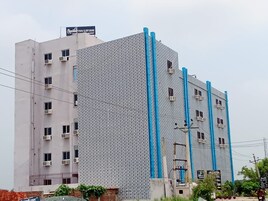 A multi-story building with a patterned facade, air conditioning units, and a sign for 'Chocolat Inn Grand.'