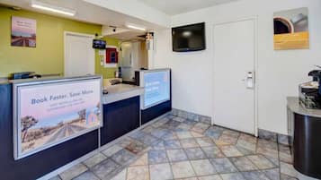 A reception area with a counter, a television mounted on the wall, and a tiled floor.