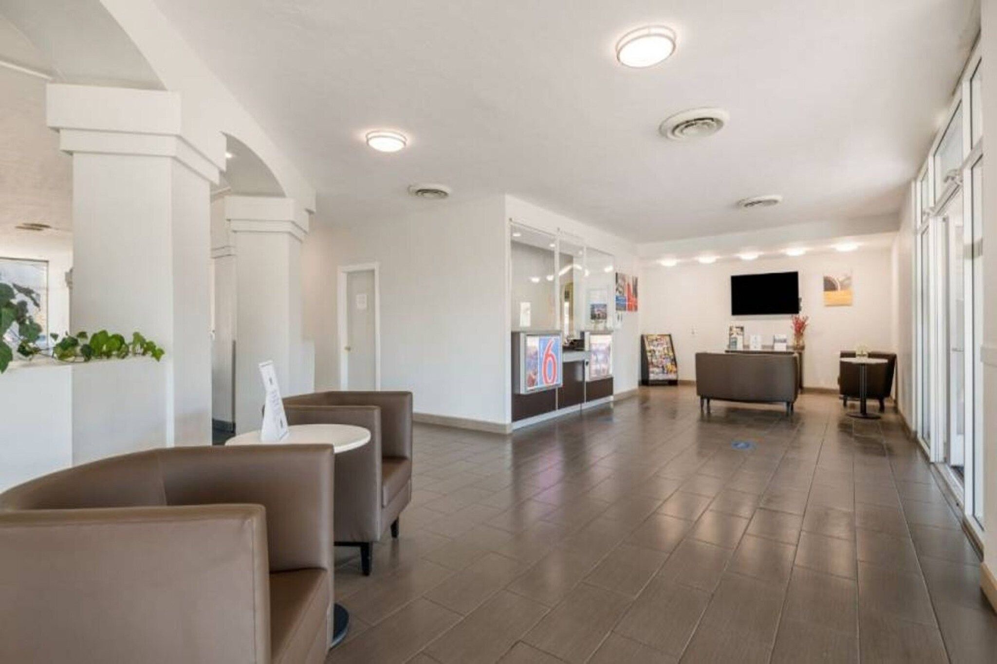 A hotel lobby with a reception desk, seating area, and a large window.