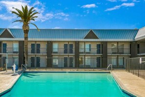 Un hôtel doté d’une piscine, de plusieurs balcons et d’un palmier.