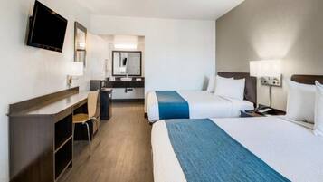A hotel room with two beds, a desk, a chair, a television, and a mirror.