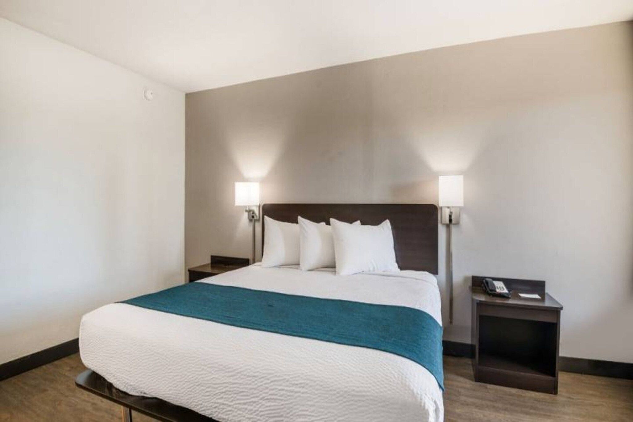 A hotel room with a large bed, two bedside tables, and a nightstand.