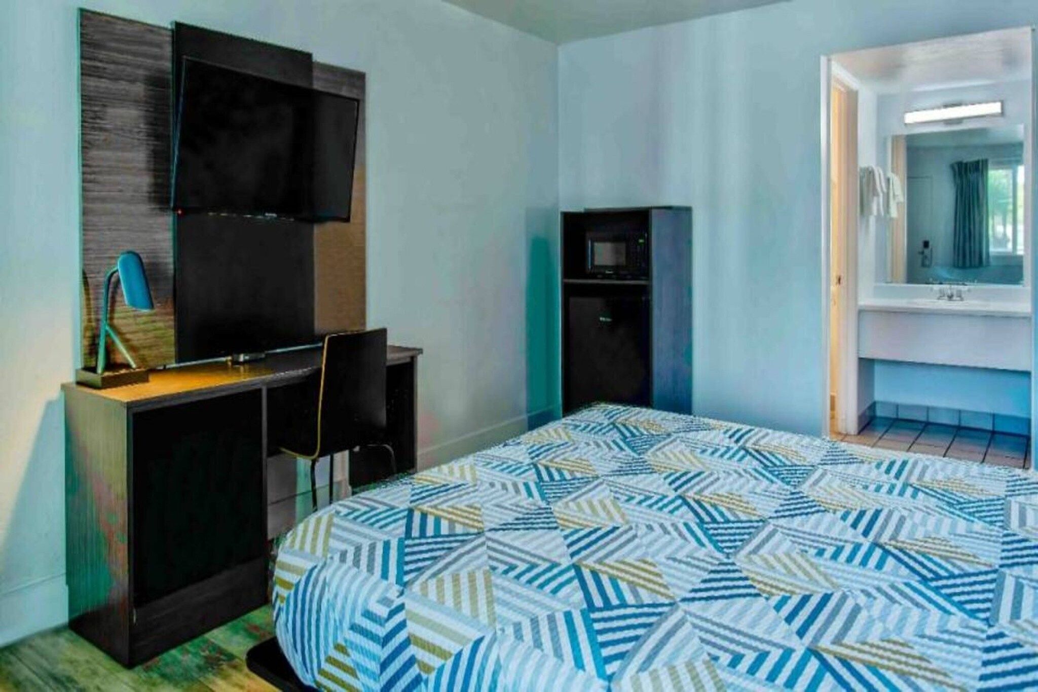 A hotel room with a bed, a desk, a television, a wardrobe, and a bathroom.