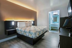 A modern bedroom with a bed, bedside tables, a desk, and a TV.