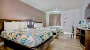 A hotel room with two beds, a desk, a chair, and a television.