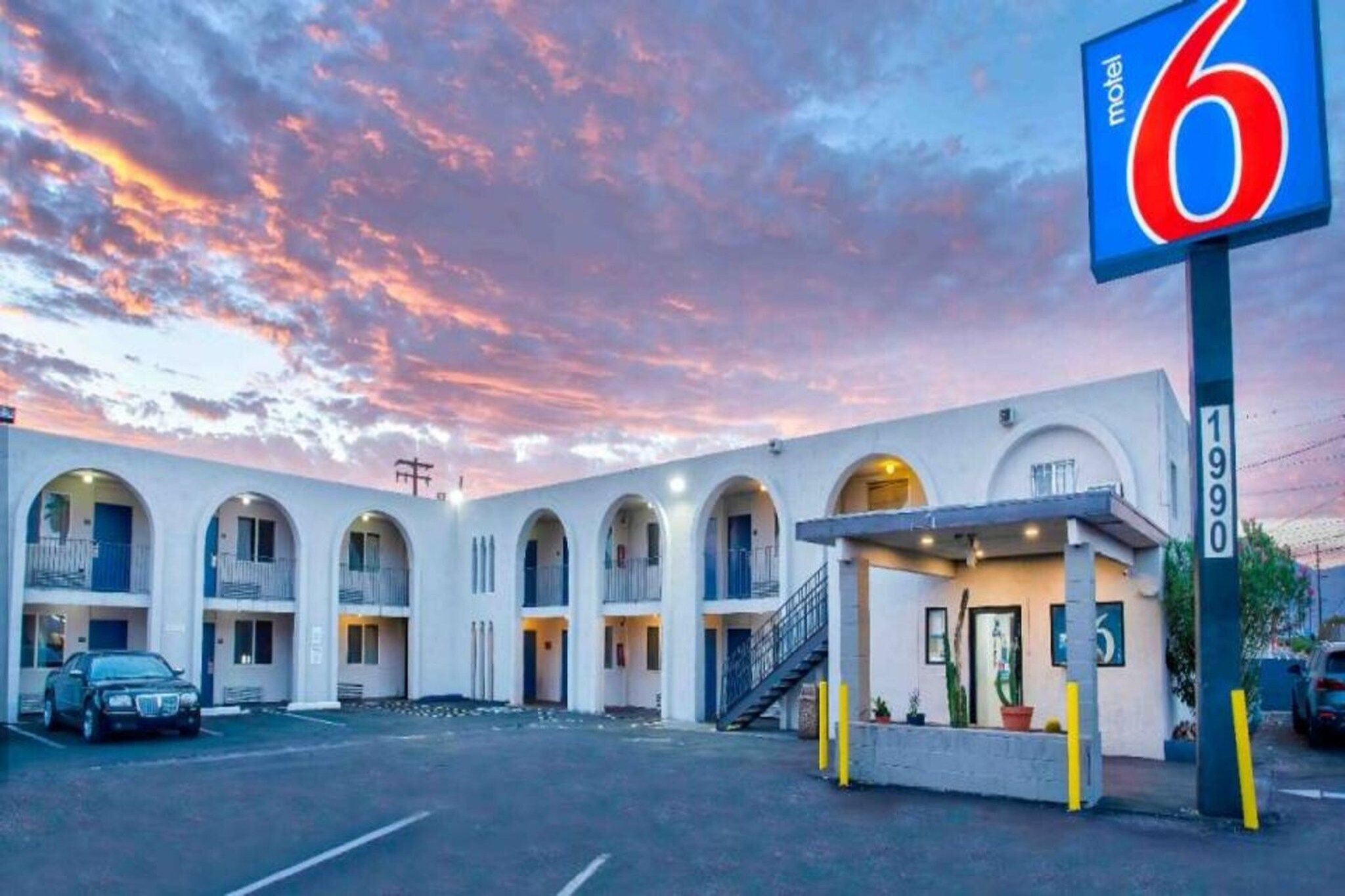 A motel with a number sign, multiple balconies, and a parking lot.