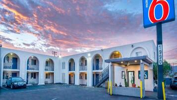 A motel with a number sign, multiple balconies, and a parking lot.