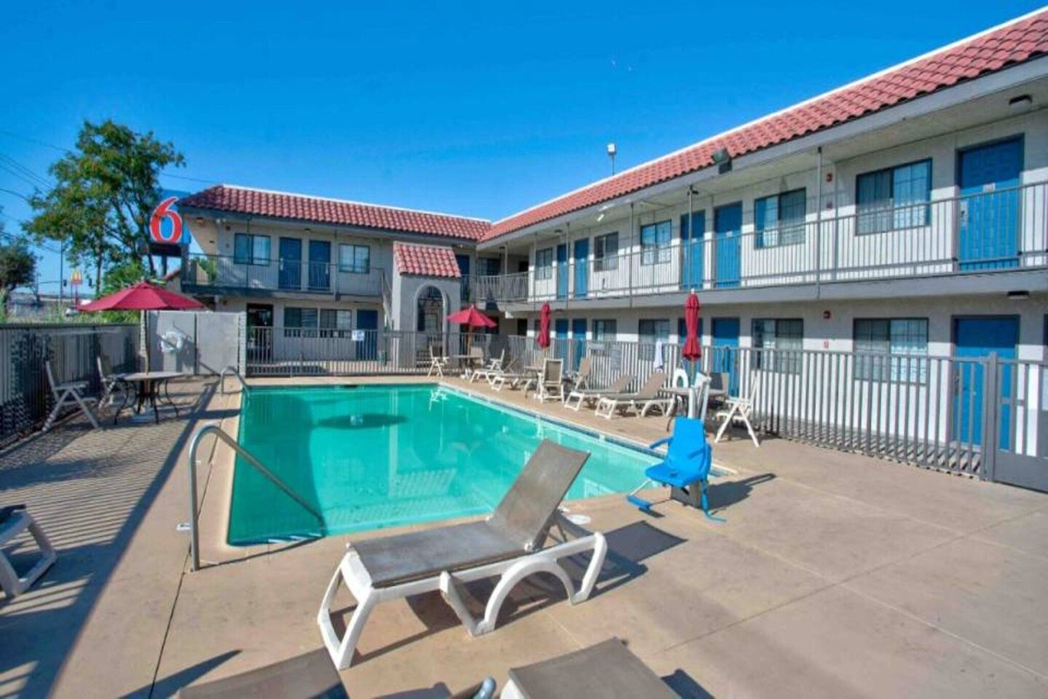A hotel with a swimming pool, outdoor seating, and a red and blue color scheme.