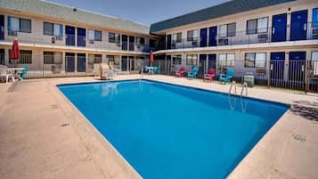 A hotel with a swimming pool, outdoor seating, and multiple balconies.