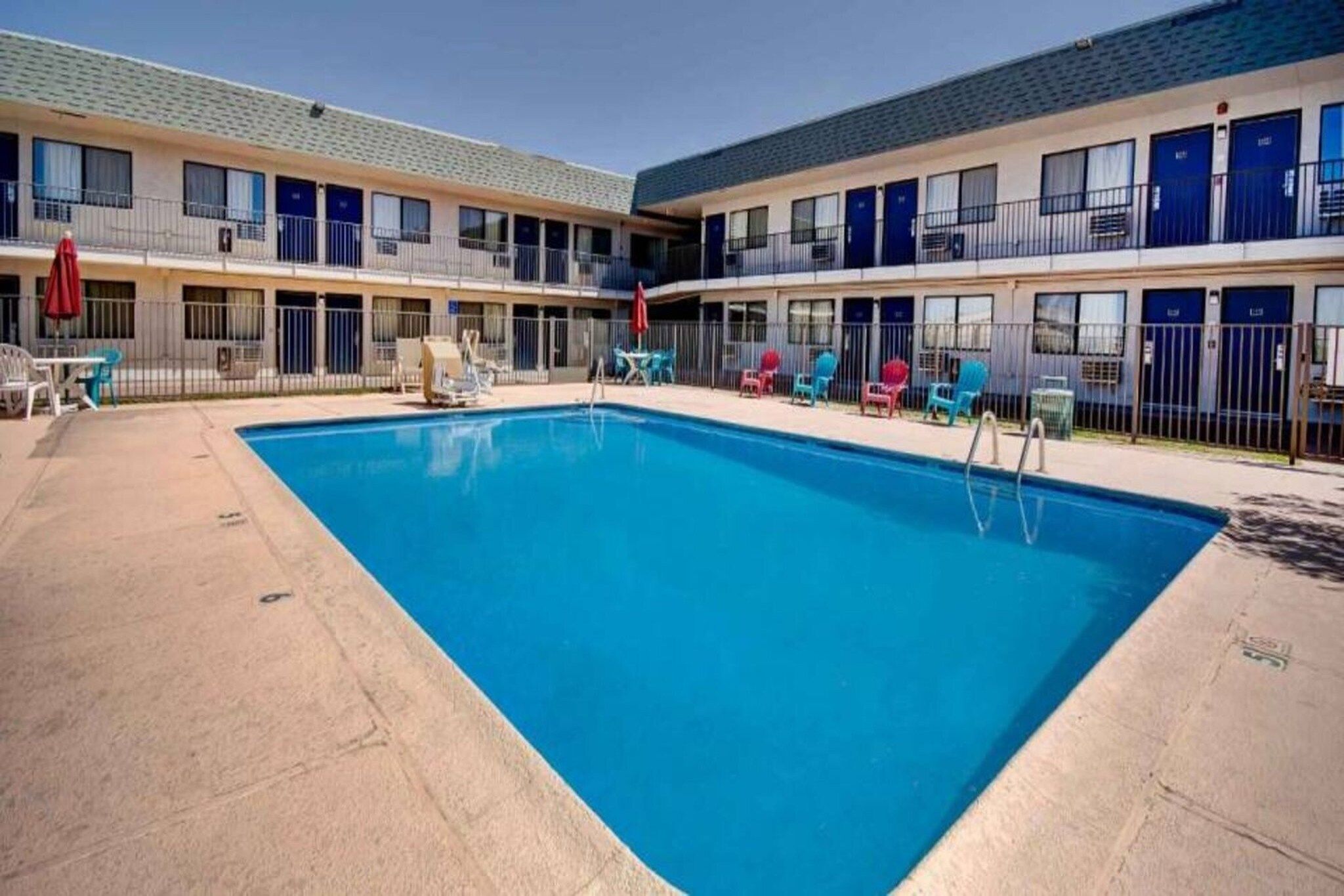 A hotel with a swimming pool, outdoor seating, and multiple balconies.