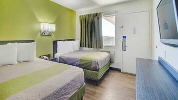 A hotel room with two beds, a television, and a door with a sign.