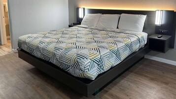 A modern bed with a geometric patterned bedspread, a dark headboard, and bedside lamps.