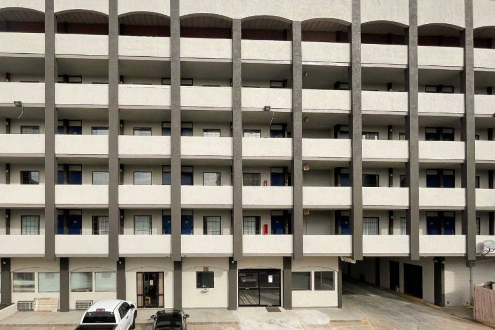 A multi-story building with a uniform facade, balconies on each floor, and a ground-level entrance.