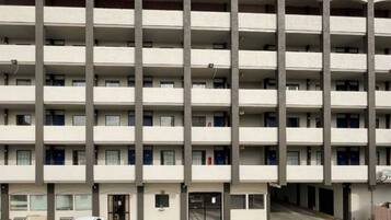 A multi-story building with a uniform facade, balconies on each floor, and a ground-level entrance.