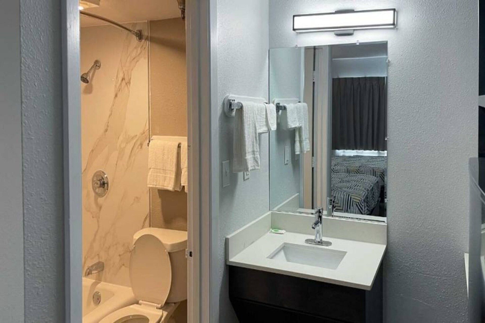 A bathroom with a toilet, a shower, a sink, and a mirror.