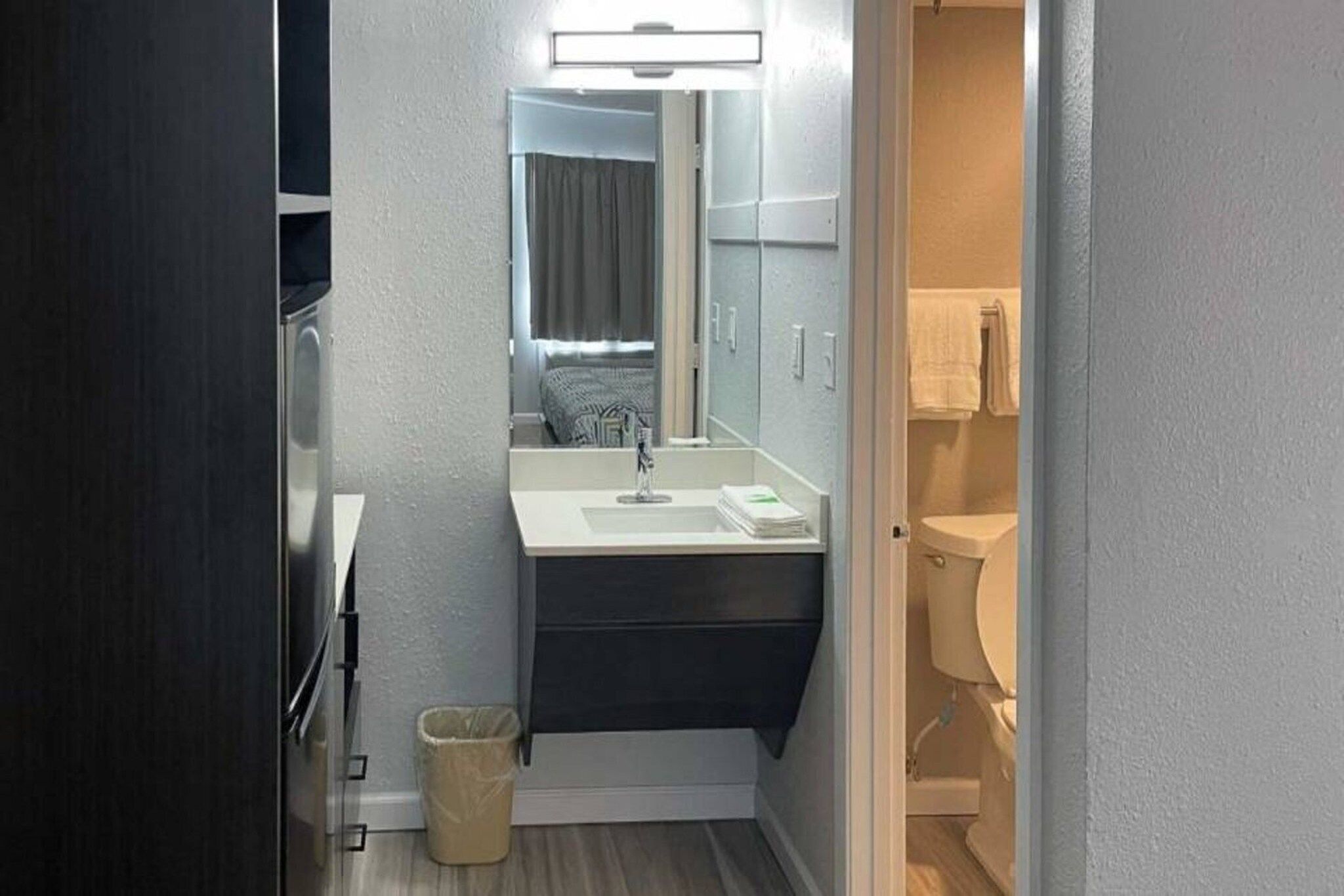 Un bany d'hotel petit amb un lavabo, mirall i vàter.