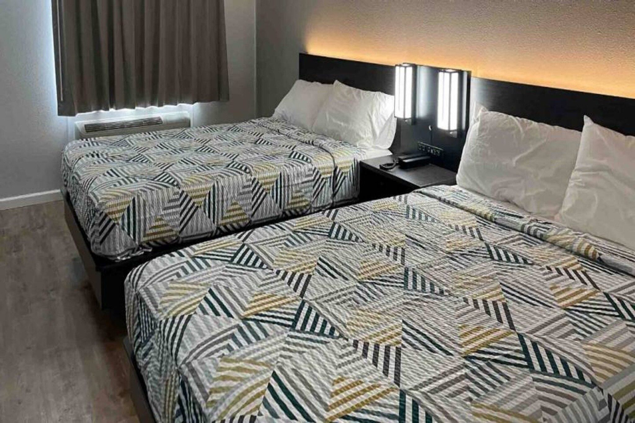 Two twin beds with patterned bedding in a hotel room.