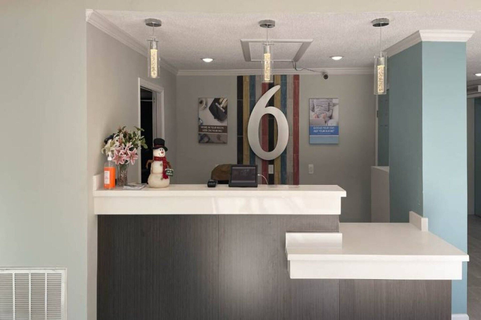 A reception desk with a large number '6' sign, a snowman decoration, and a vase of flowers.