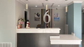 A reception desk with a large number '6' sign, a snowman decoration, and a vase of flowers.