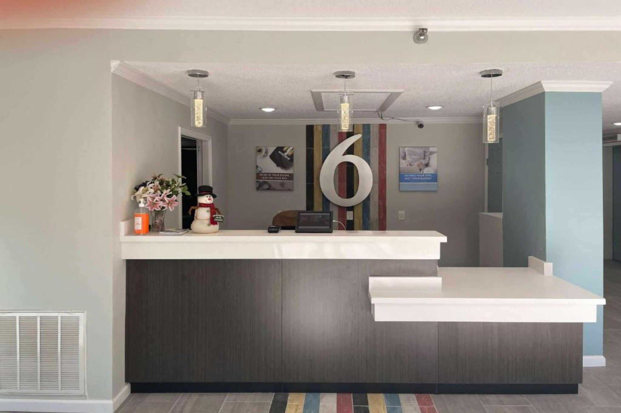 A reception desk with a large number '6' sign, a vase with flowers, and a snowman decoration.