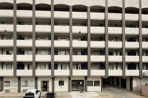 A multi-story building with a uniform facade, balconies on each floor, and a ground-level entrance.