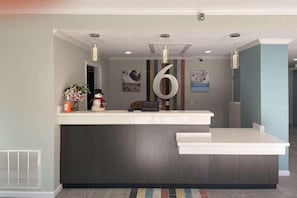 A reception desk with a large number '6' sign, a vase with flowers, and a snowman decoration.