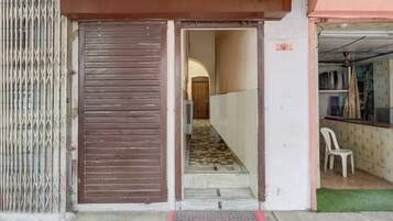 Uma porta de entrada para um corredor com chão de azulejos e uma cadeira branca.