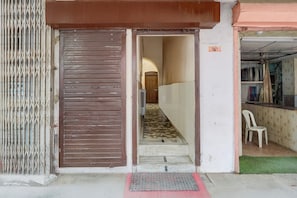 A doorway leading to a hallway with a tiled floor and a white chair.