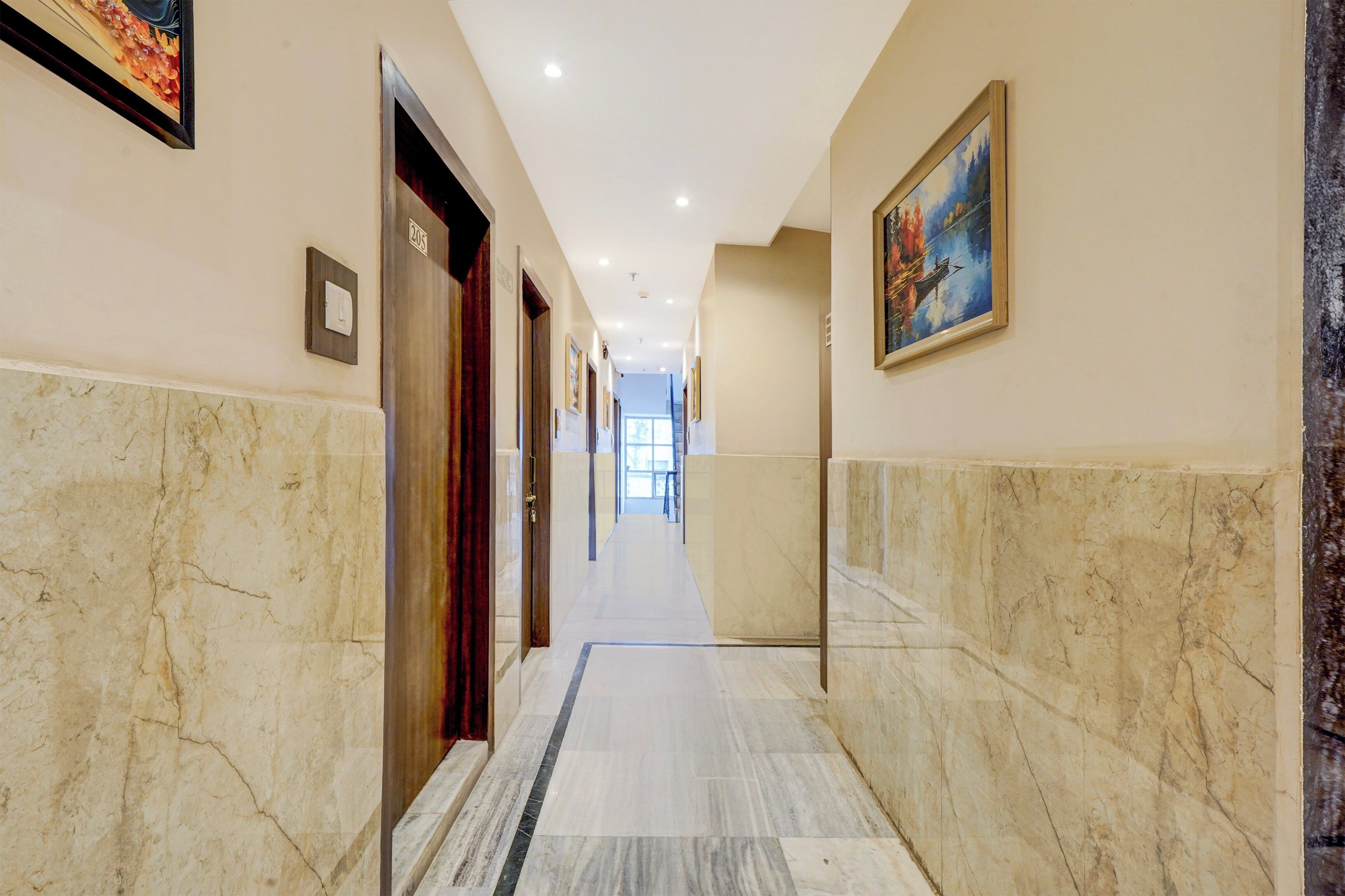 A hallway with marble flooring, doors, and framed artwork on the walls.