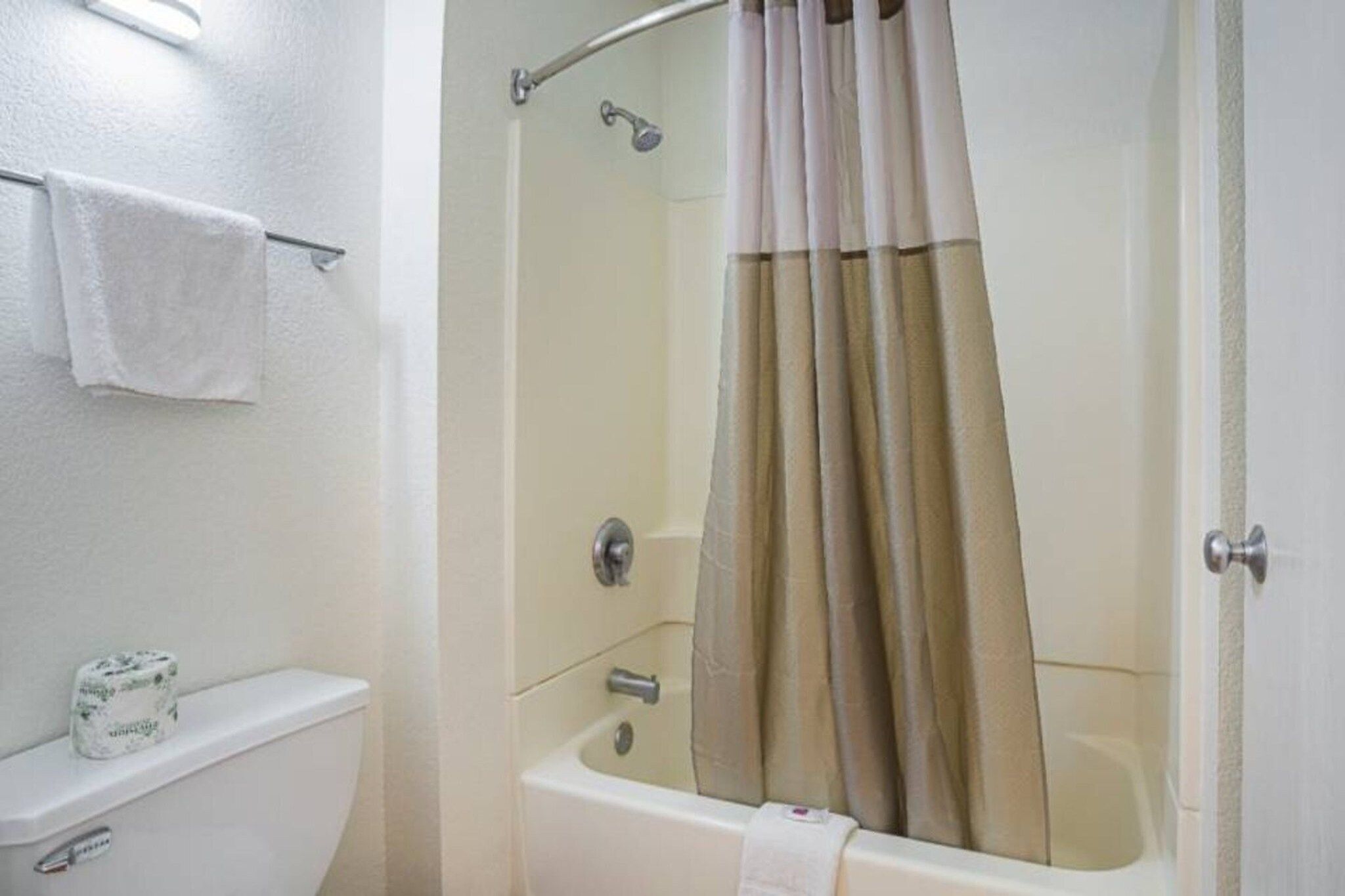 A bathroom with a bathtub, a toilet, and a shower curtain.