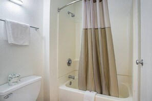 A bathroom with a bathtub, a toilet, and a shower curtain. - 1 Queen Bed | Smoking (Yuma AZ)