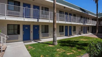 A two-story motel with blue doors, a covered parking area, and a small lawn.