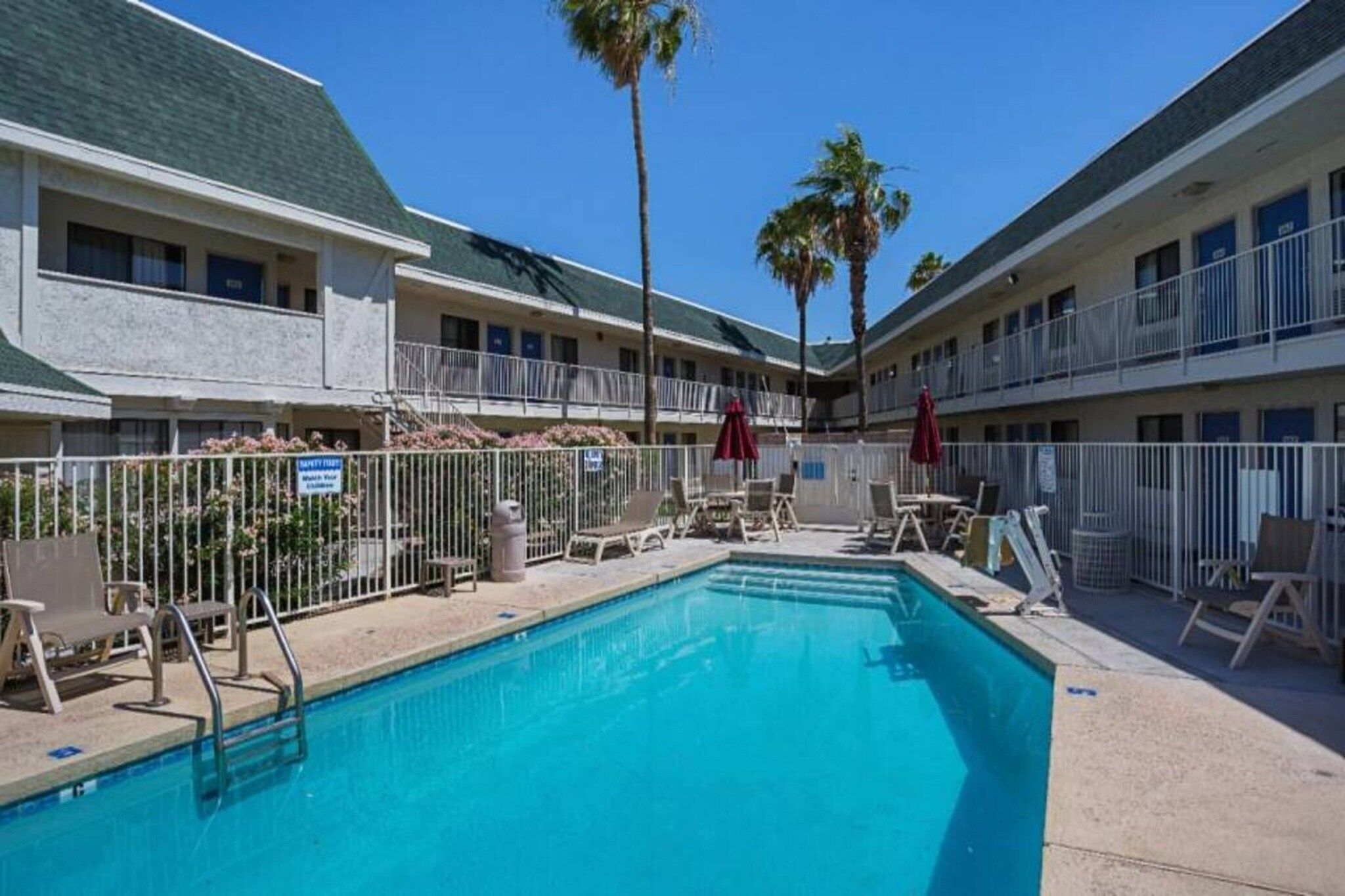 Un hôtel doté d’une piscine, de chaises longues et d’un espace clôturé.