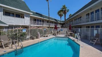 Un hôtel doté d’une piscine, de chaises longues et d’un espace clôturé.