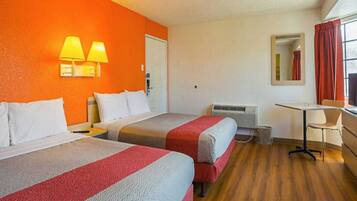 A hotel room with two beds, a desk, a chair, a mirror, and a window with curtains.