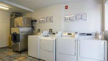 Un cuarto de lavandería con cuatro lavadoras, un refrigerador grande y un calentador de agua.