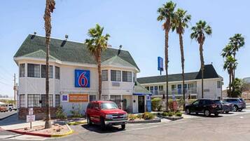 A motel with a '6' sign, multiple parking spaces, and palm trees.
