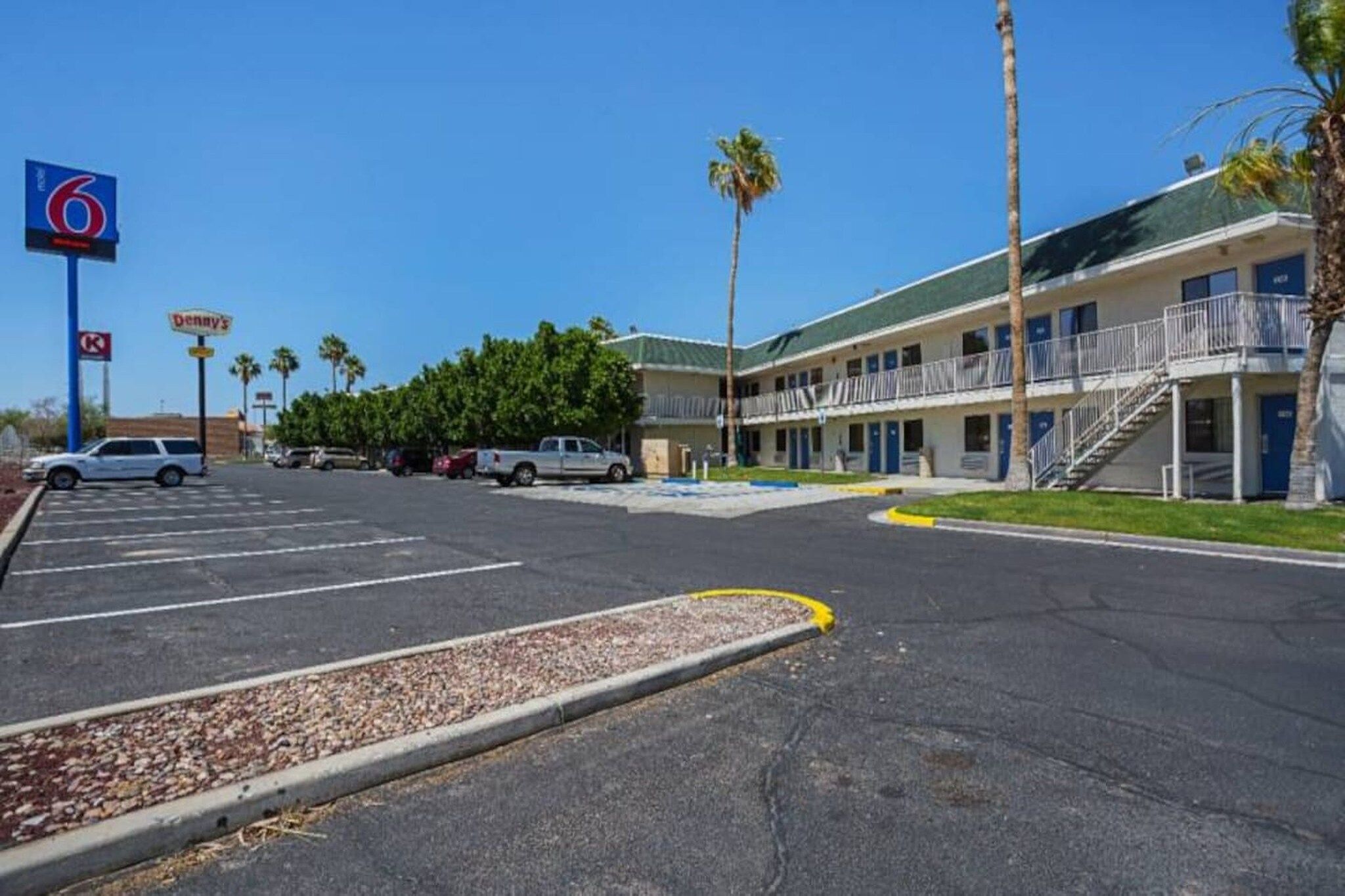 A motel with a parking lot, a sign for Denny's, and a 6 Motel sign.