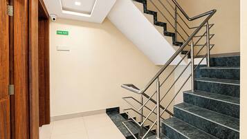 A staircase with a fire exit sign, a security camera, and a wooden door.