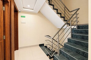 Una escalera con un letrero de salida de incendios, una cámara de seguridad y una puerta de madera.